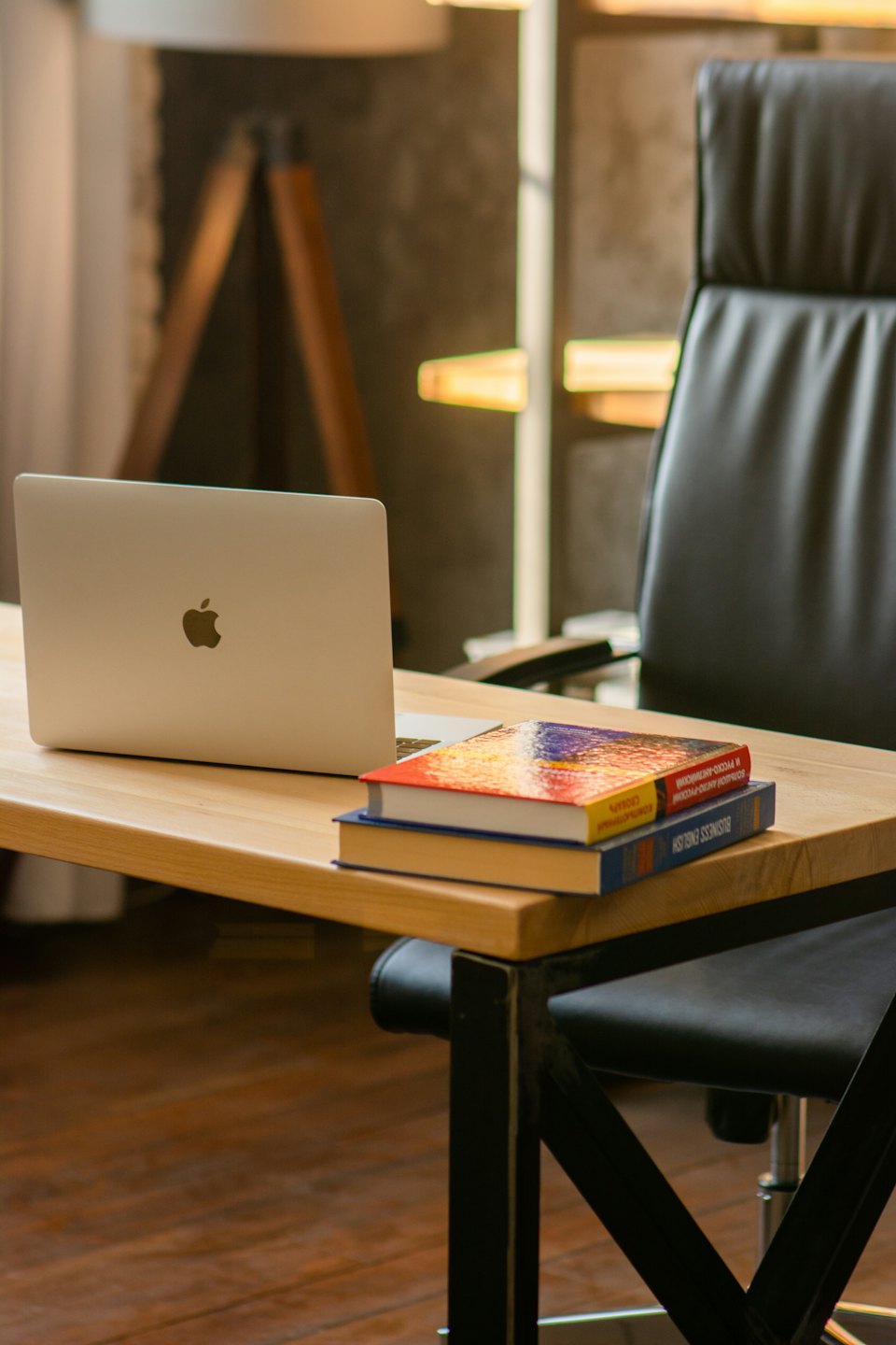 Silberner Laptop und Bücher auf einem Holztisch.